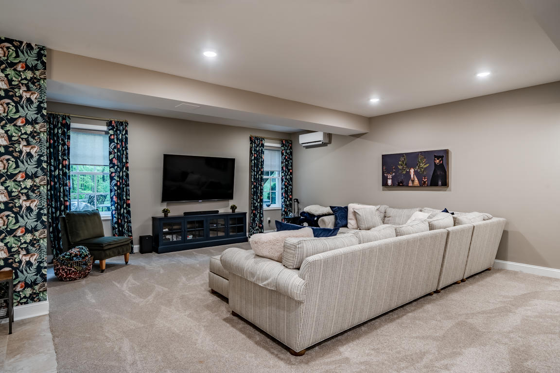 Carriage Path media room — large sectional, accent wallpaper, recessed lighting, wall-mounted TV, mini-split