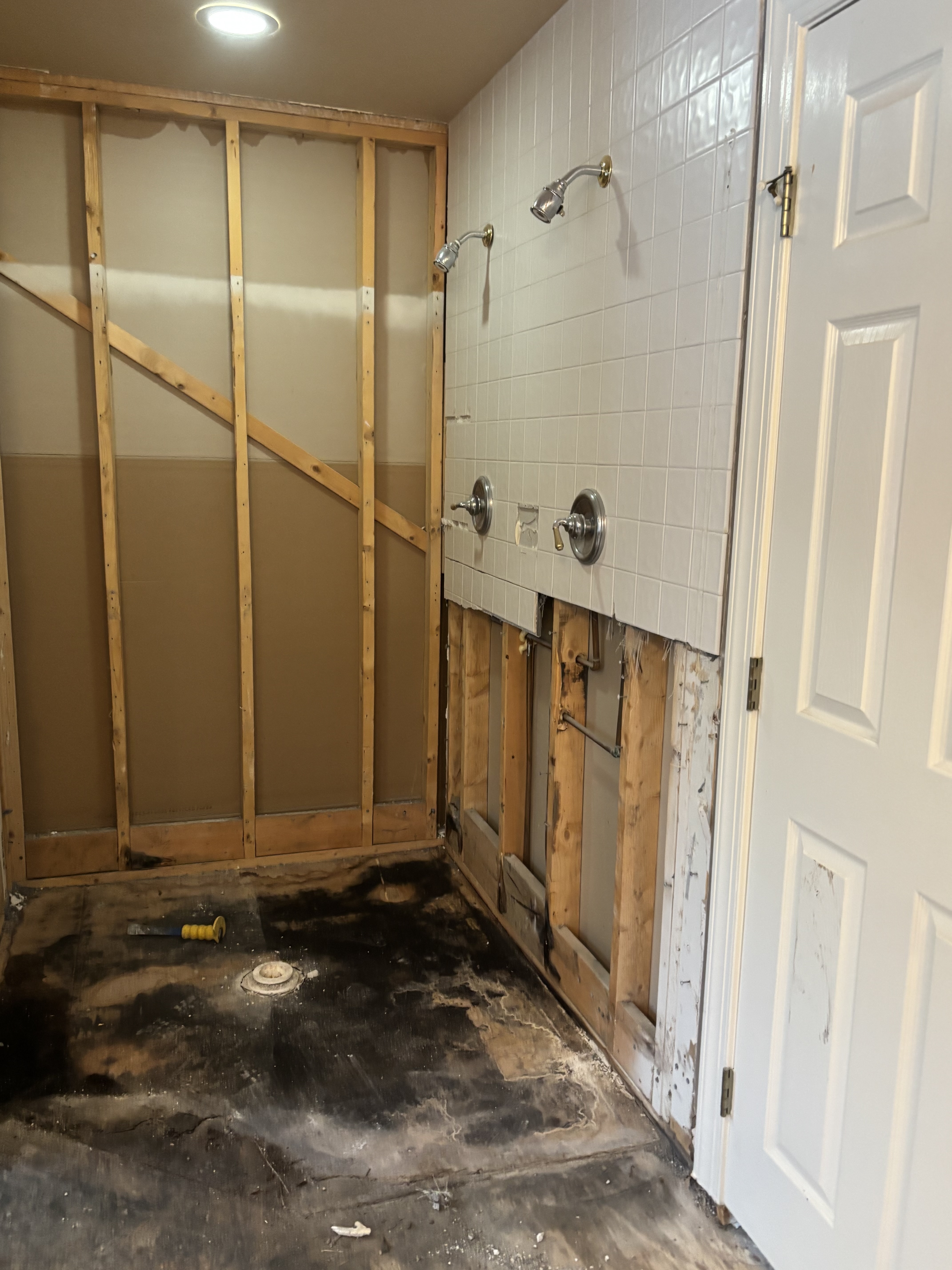 Demolition of shower revealing water damage behind tile and rotted framing from failed waterproofing
