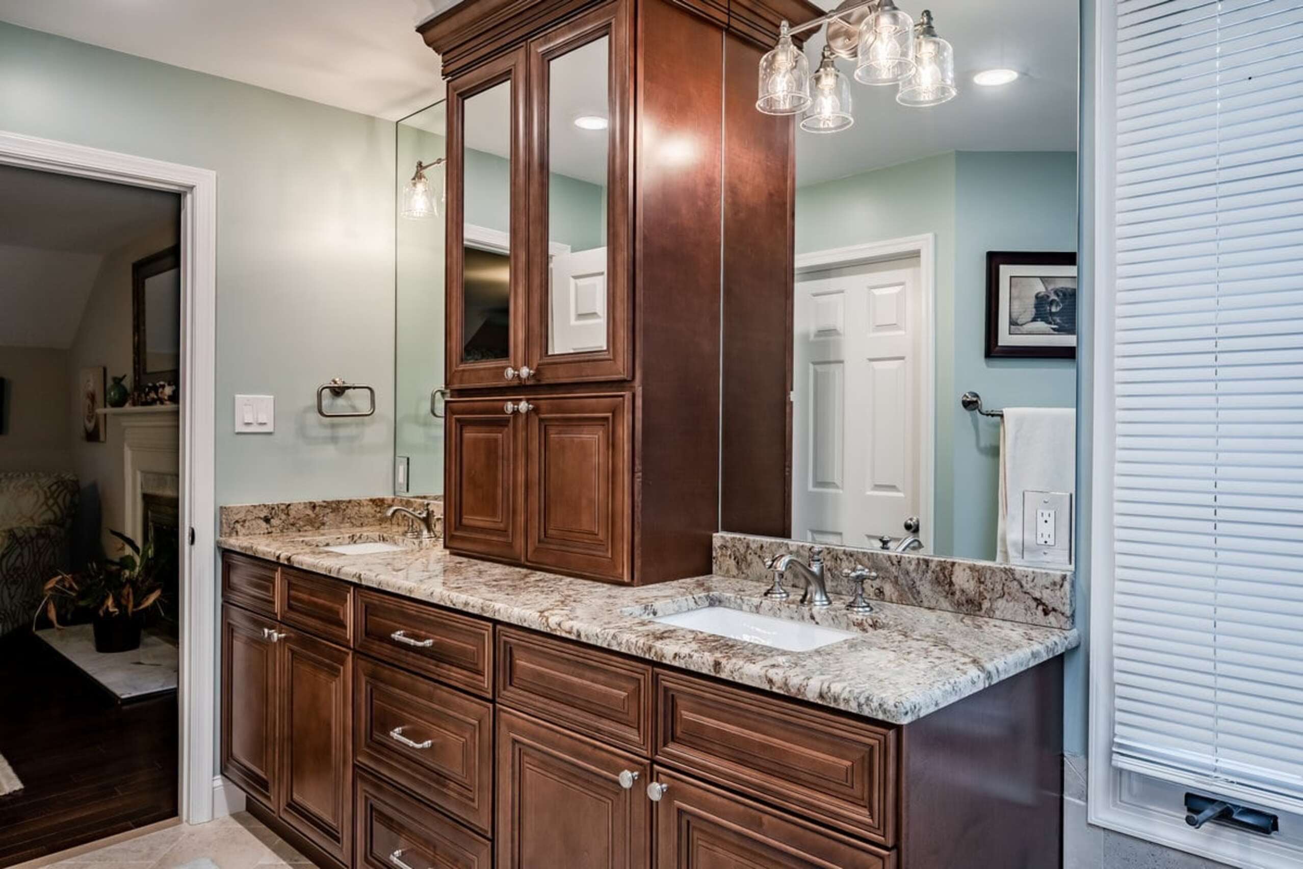 Chadds Ford bathroom double vanity with dark cherry cabinetry, granite countertops, and glass light fixtures