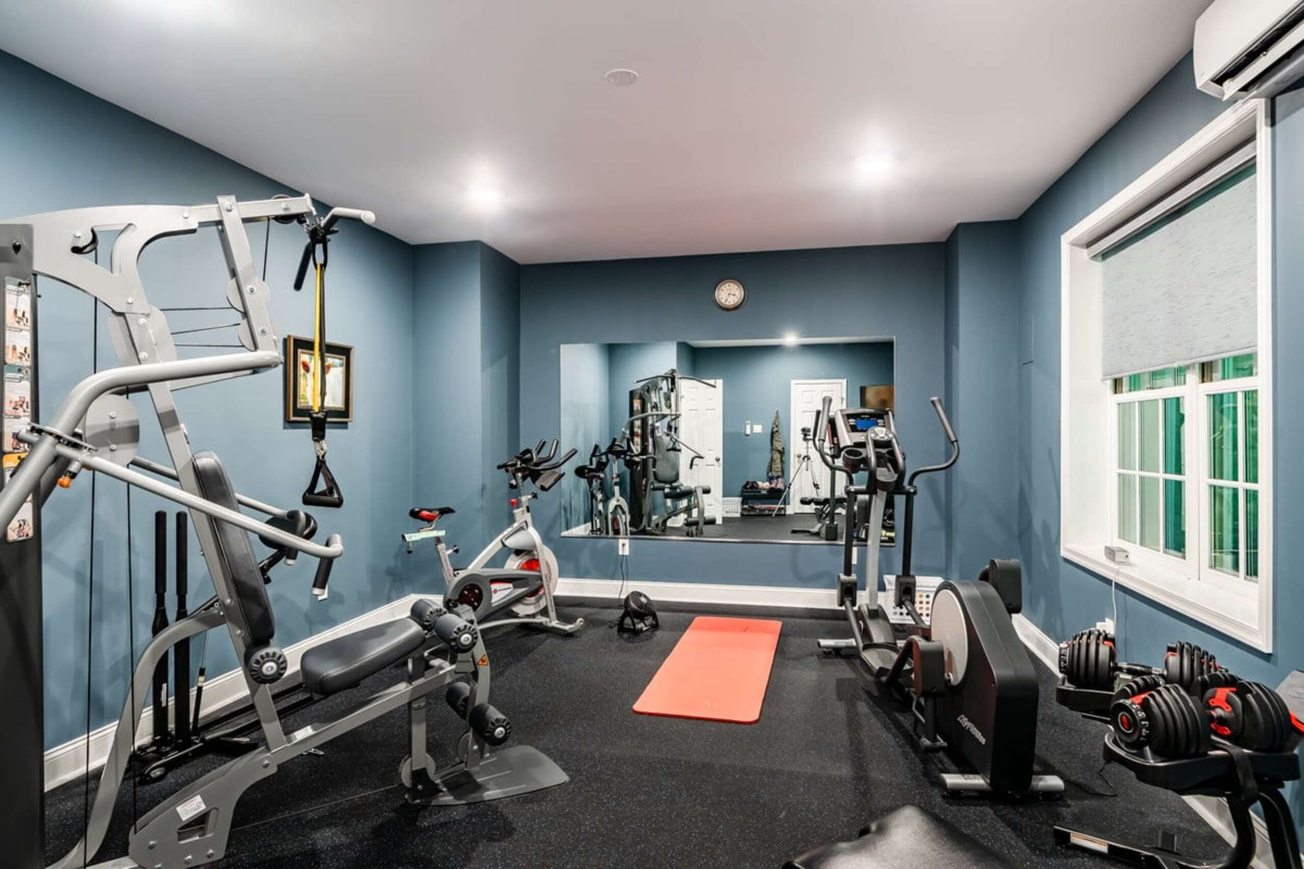 Chadds Ford basement home gym with blue walls, rubber flooring, and full exercise equipment setup