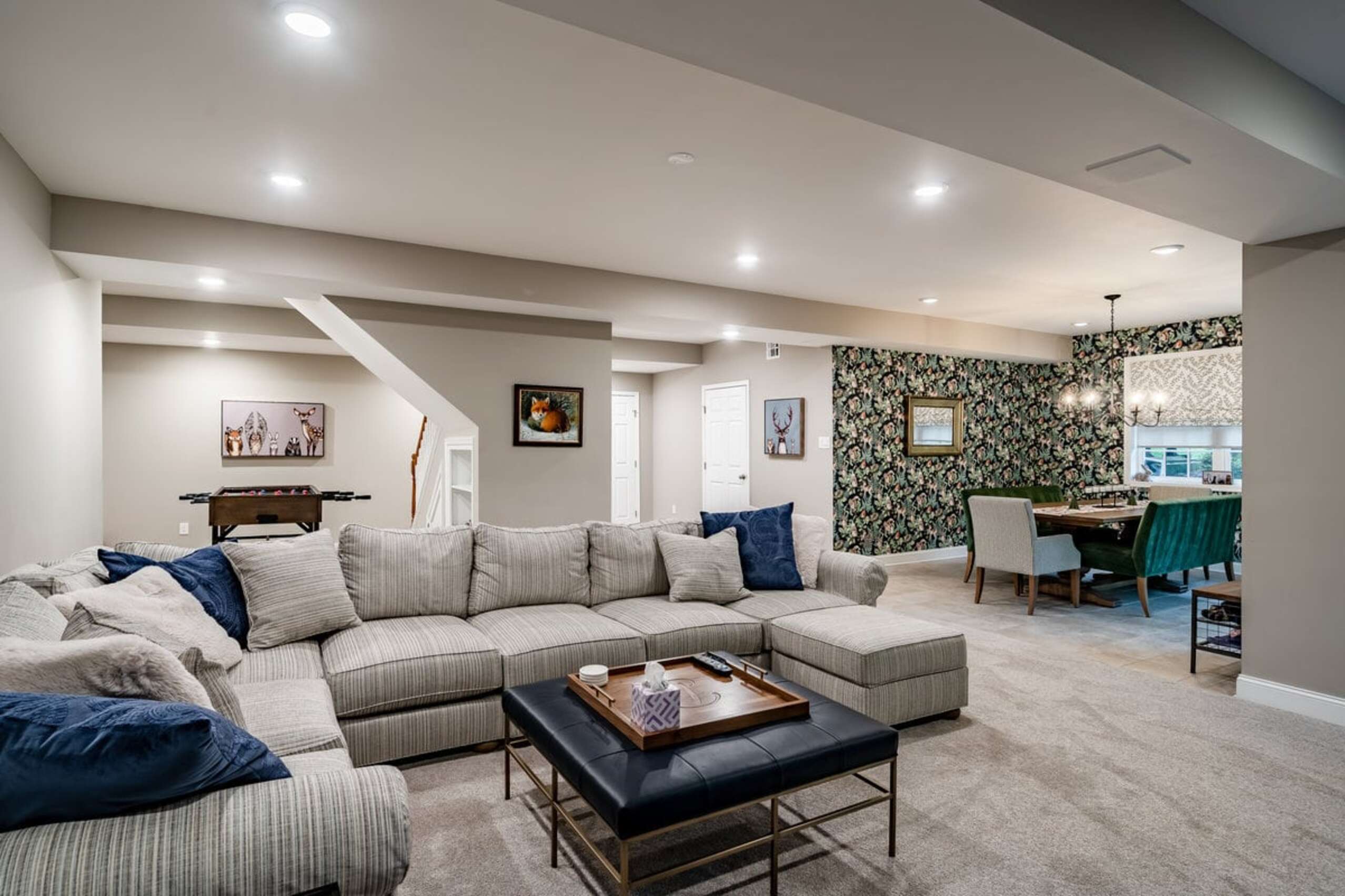 Chadds Ford basement living area with sectional sofa, foosball table, floral wallpaper accent dining area