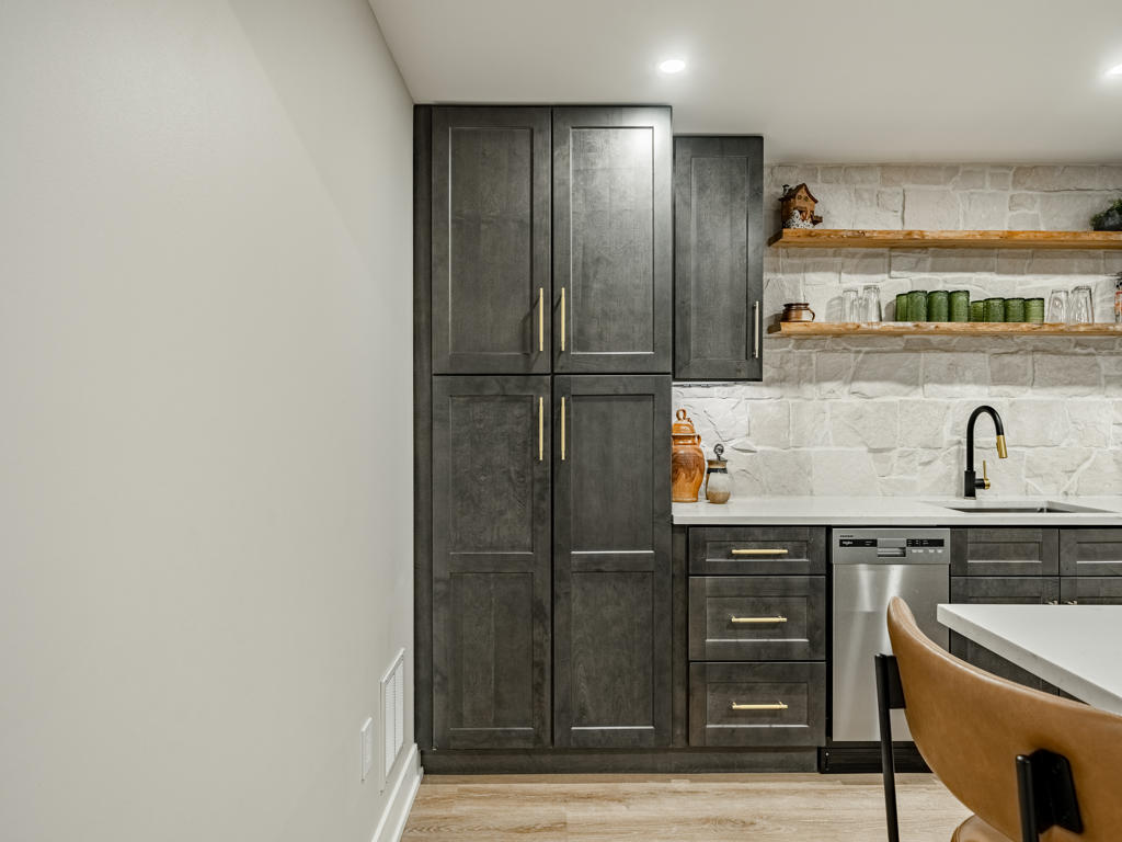 Tall charcoal pantry cabinet detail beside undermount sink and stone backsplash in Chester Springs basement kitchenette