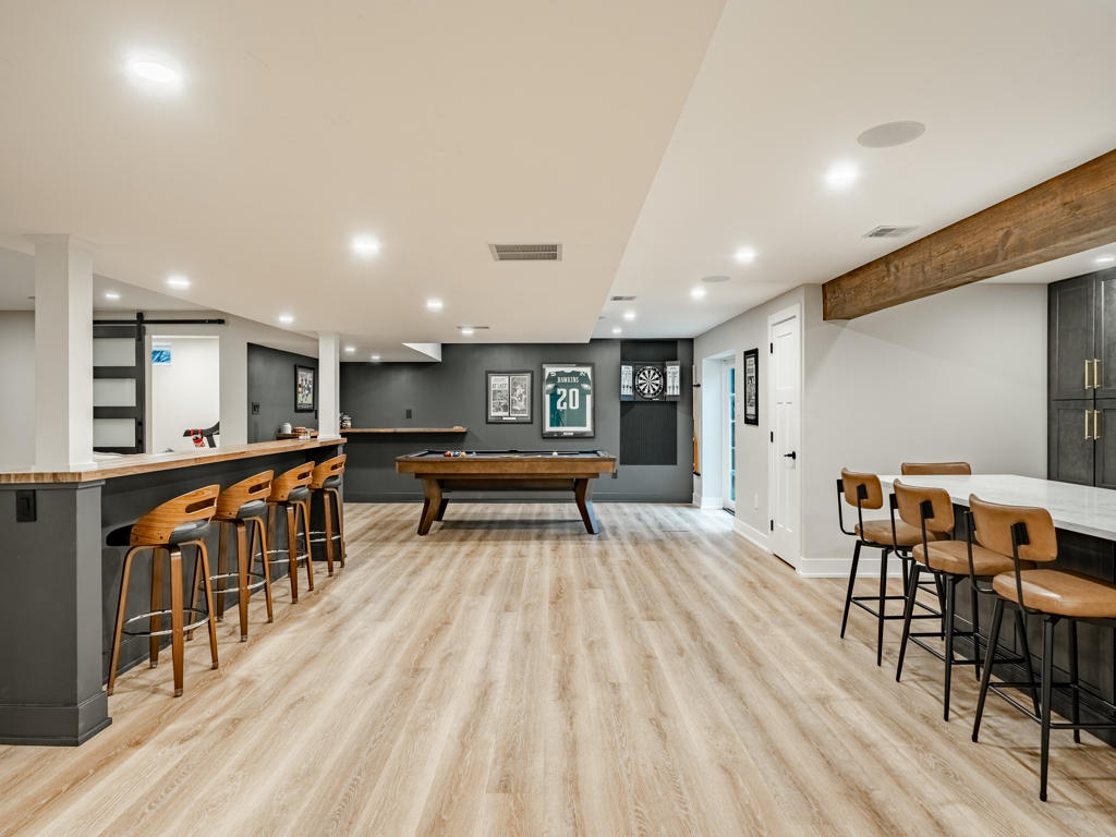 Full basement remodel in Chester Springs PA featuring custom wet bar with charcoal shaker cabinets, pool table game room, and open entertainment space