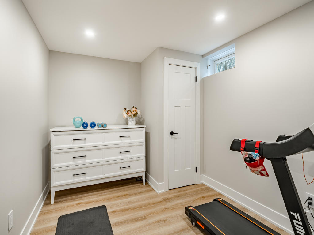 Dedicated home gym room in Chester Springs finished basement with treadmill, wall-mounted TV, and open floor space