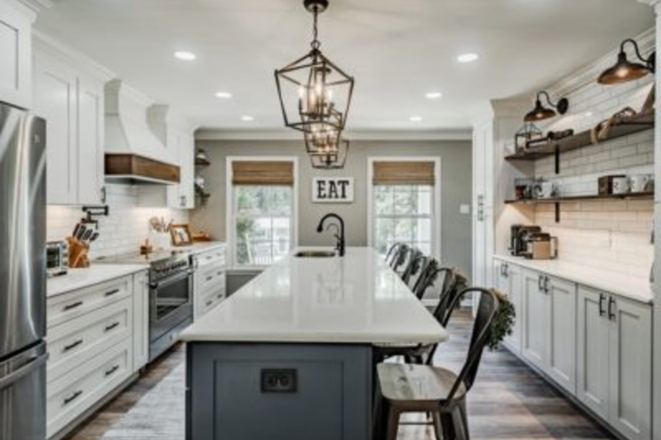 Downingtown farmhouse kitchen with white cabinets, blue island, iron lantern pendants, and EAT sign