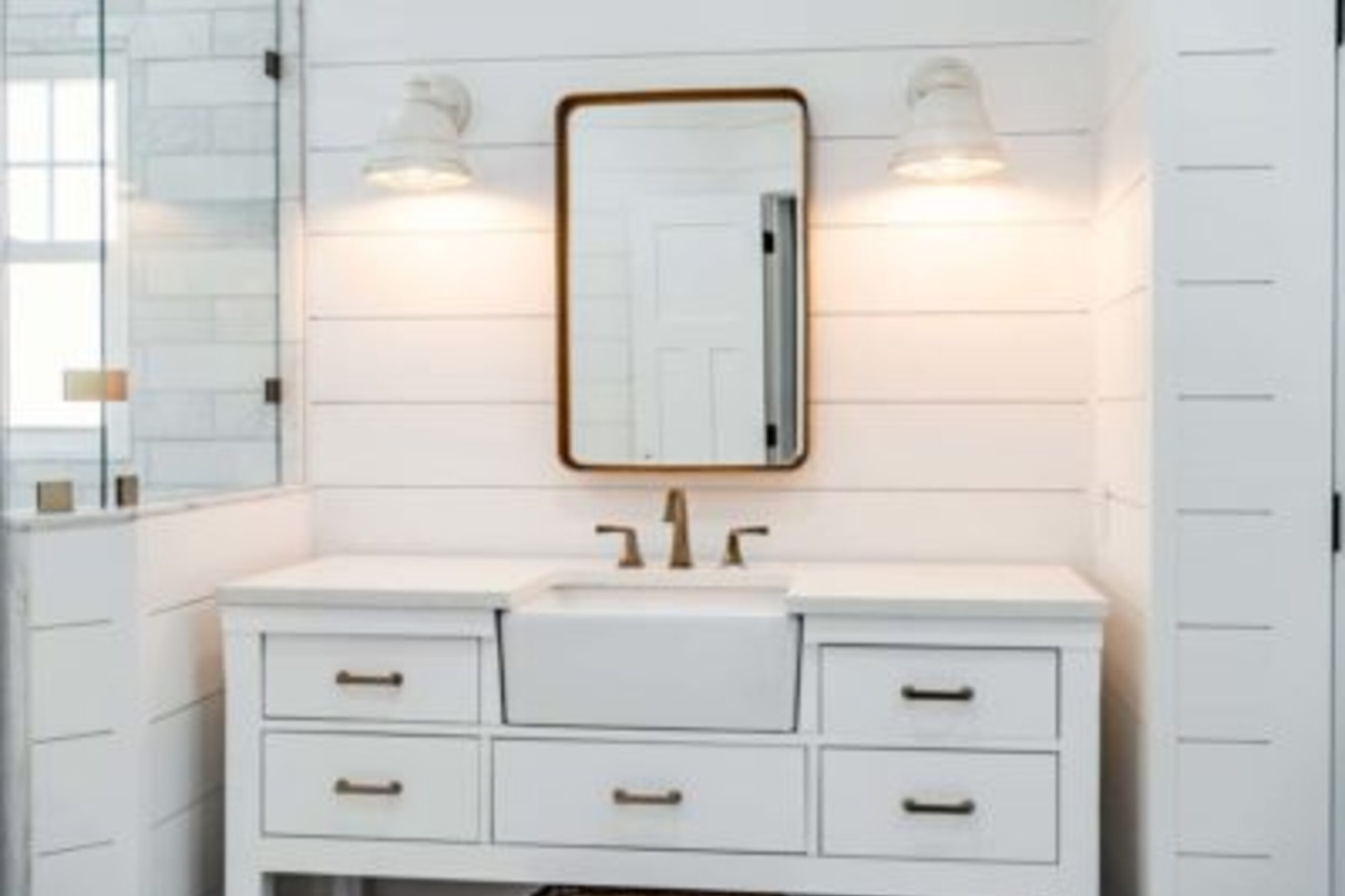 Downingtown farmhouse bathroom white vanity with shiplap walls, brass fixtures, and rounded mirror