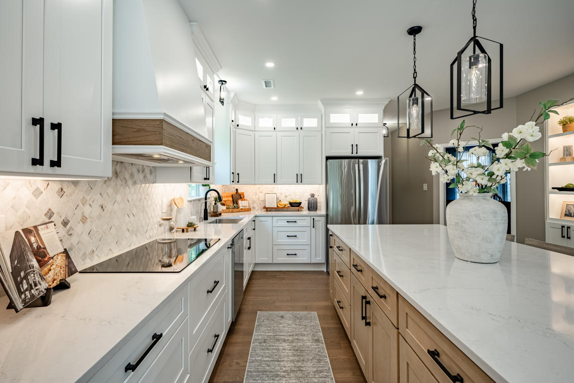 Kitchen view from dining area showing white cabinets, arabesque backsplash, French-door refrigerator, natural oak island base, and floating shelves