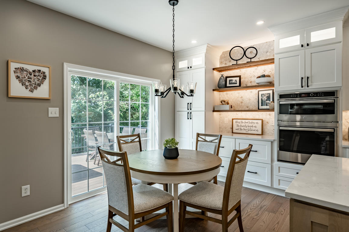 Kitchen island detail with natural oak base cabinets, matte black bar-pull hardware, quartz countertop with marble veining, and iron lantern pendants above