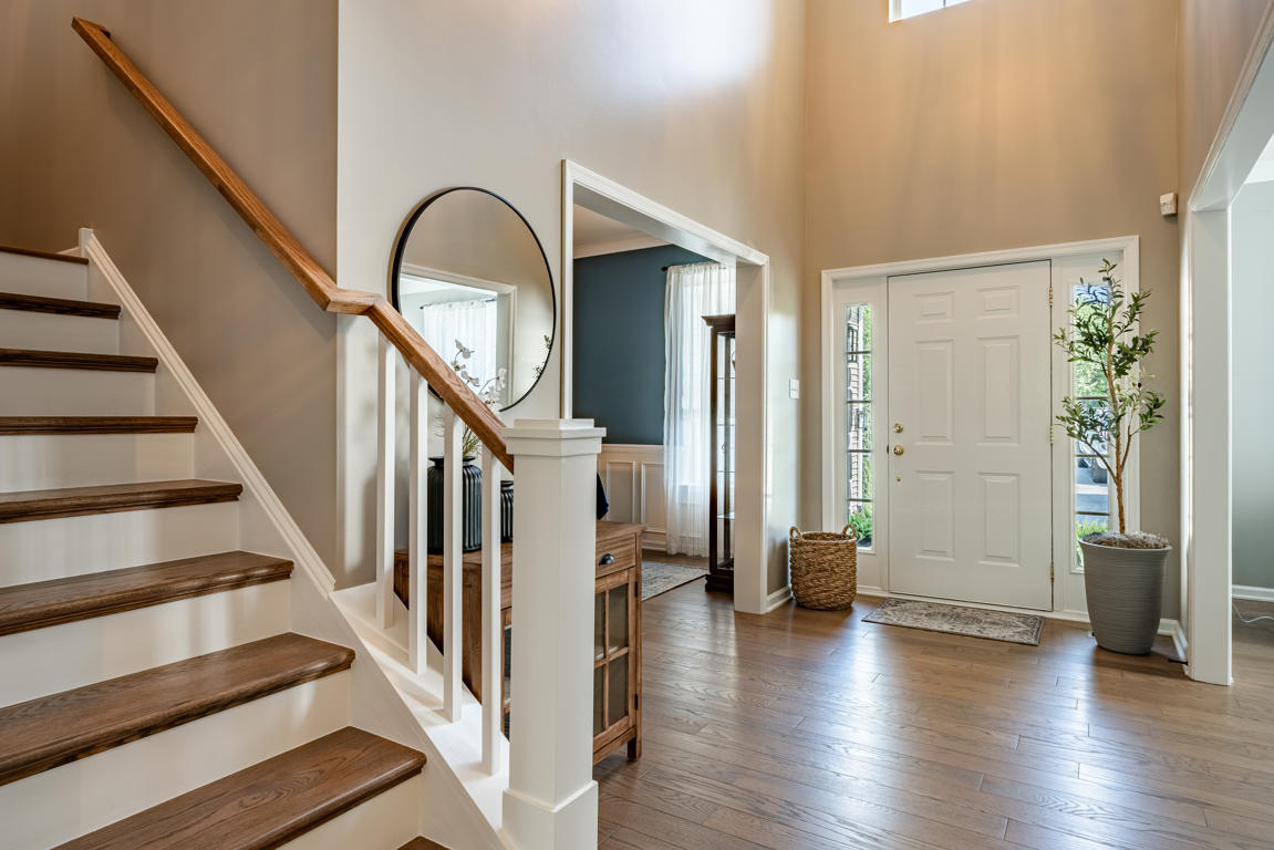 Two-story foyer with refinished hardwood floors, stained oak stair treads with white painted risers, white balusters, and oak handrail