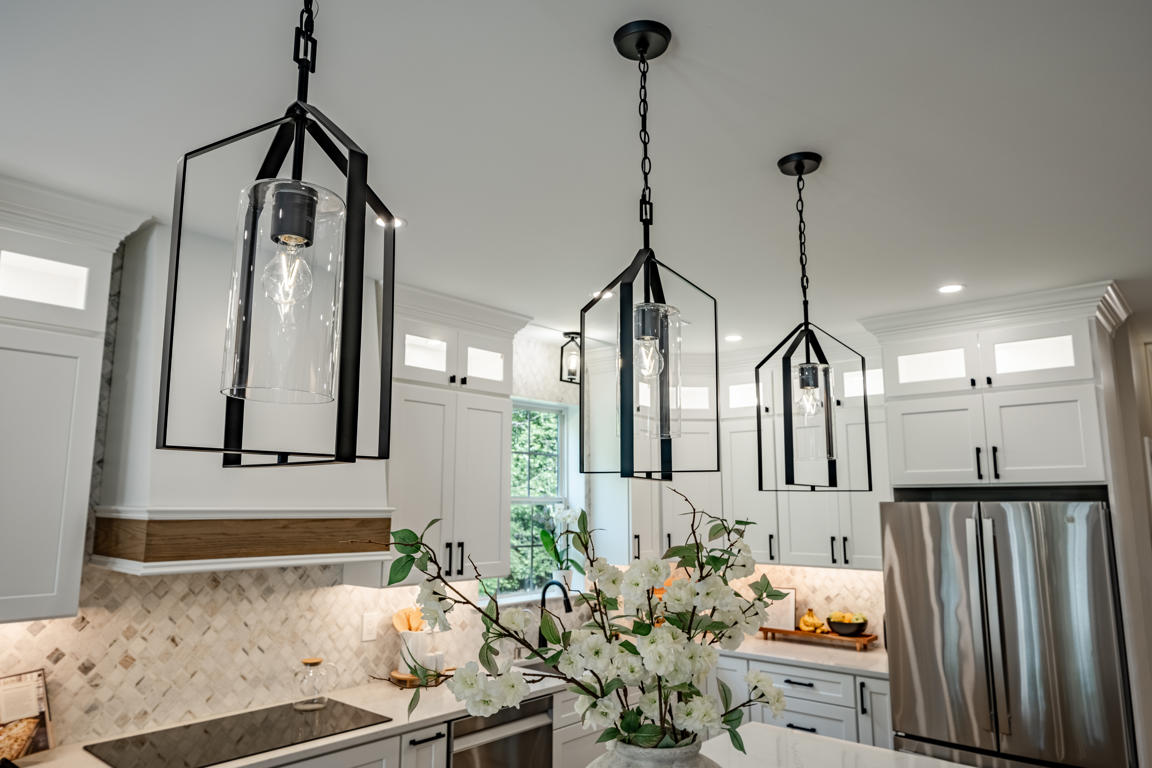 White shaker perimeter cabinets with matte black hardware, quartz countertops, and arabesque marble backsplash running full height to upper cabinets