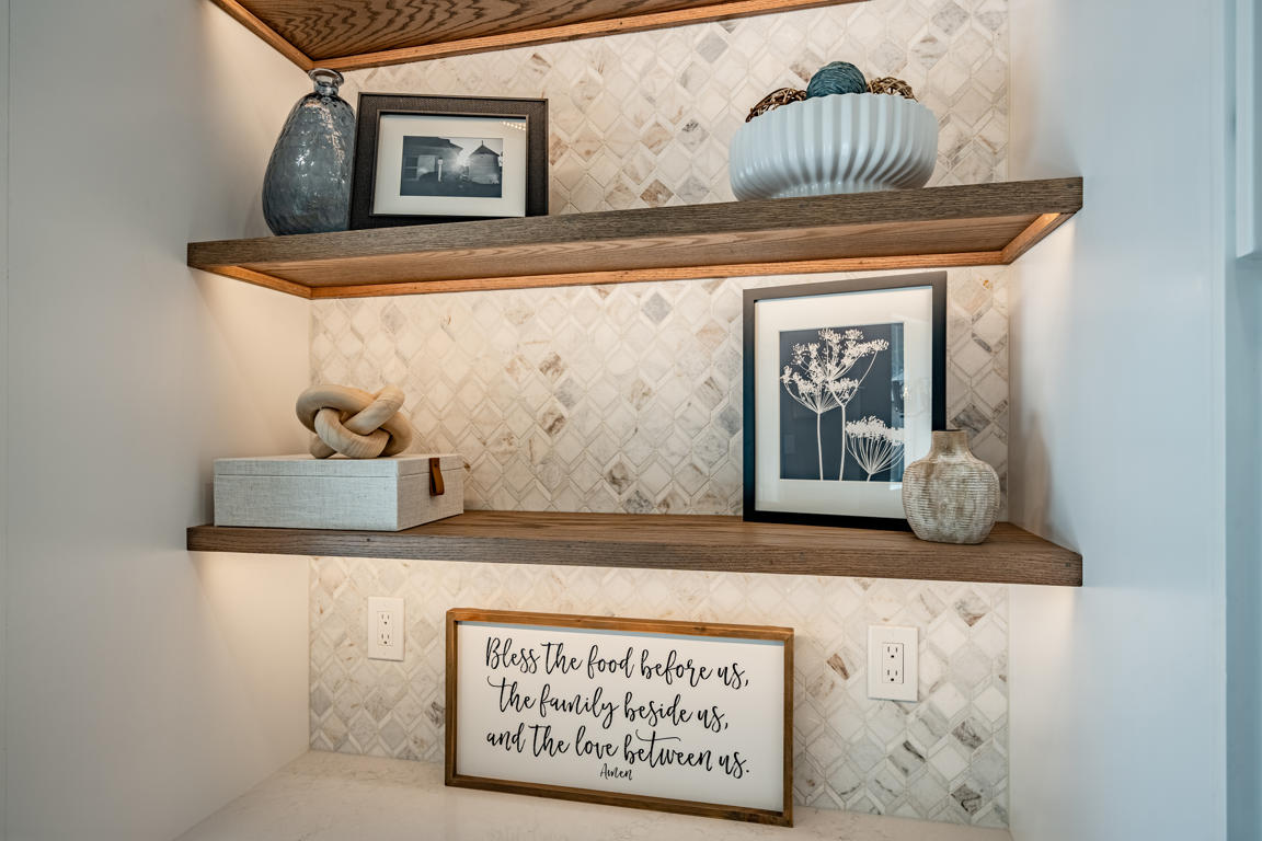 Built-in living room display shelving with warm LED accent lighting, open shelves for books and decor, and closed shaker cabinets below