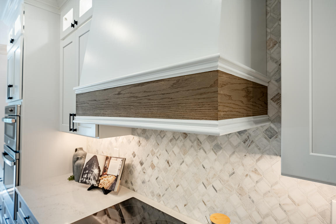 Open-concept view from kitchen island through to dining area and living room with built-in shelving, showing continuous hardwood floors throughout