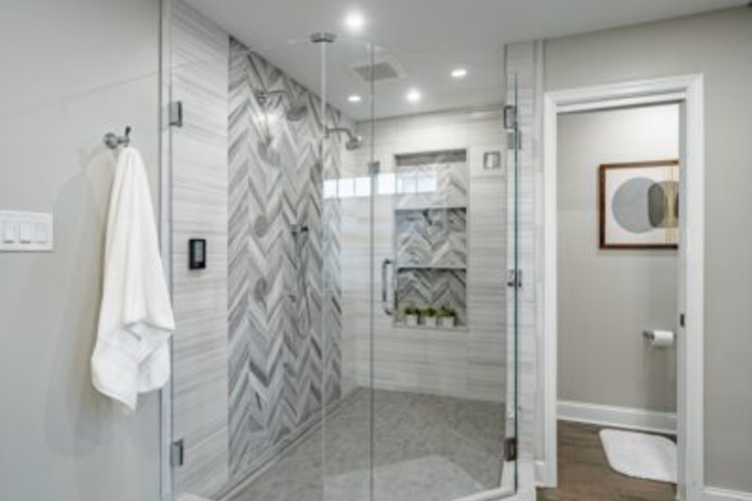 Downingtown luxury bathroom chevron marble tile walk-in shower with glass enclosure and rain showerhead
