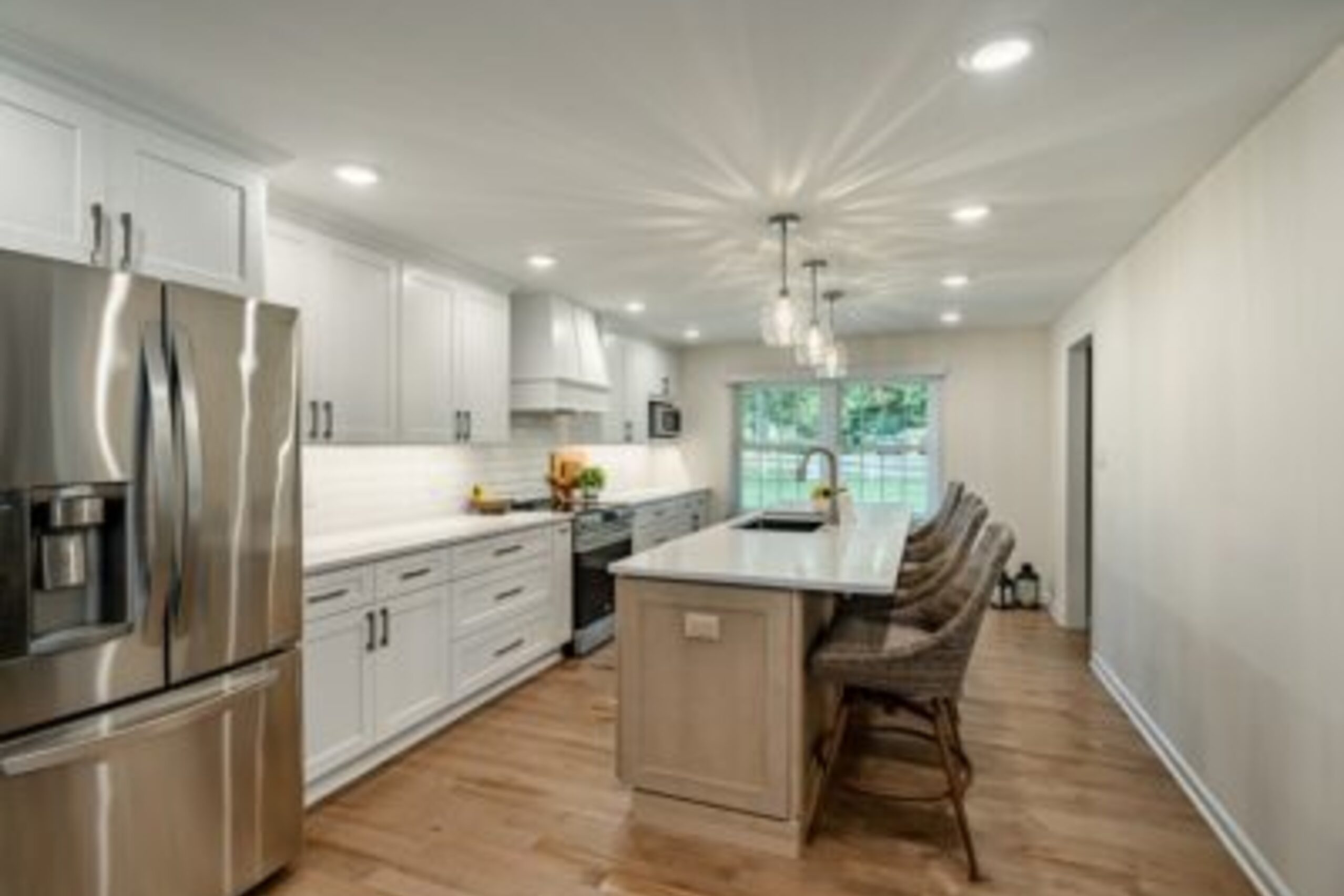 Downingtown open concept kitchen with white cabinets, two-tone island, globe pendants, and bar seating