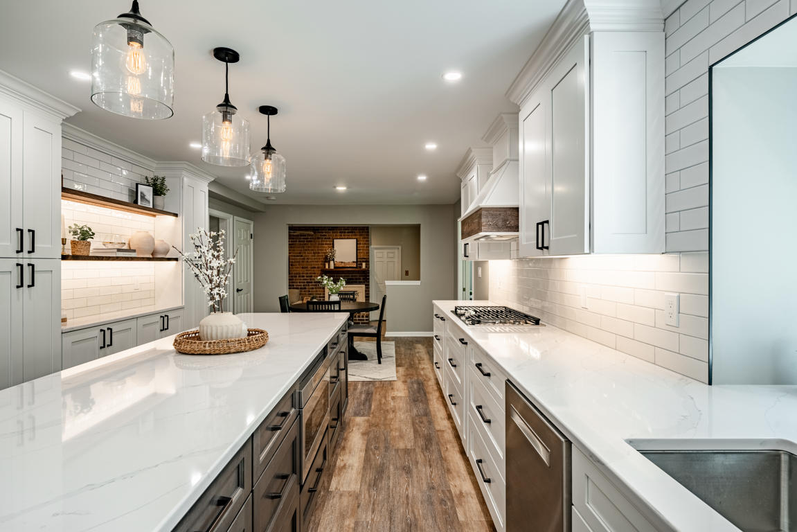 Kitchen island with glass pendant lights, built-in display niche, and abundant white cabinetry
