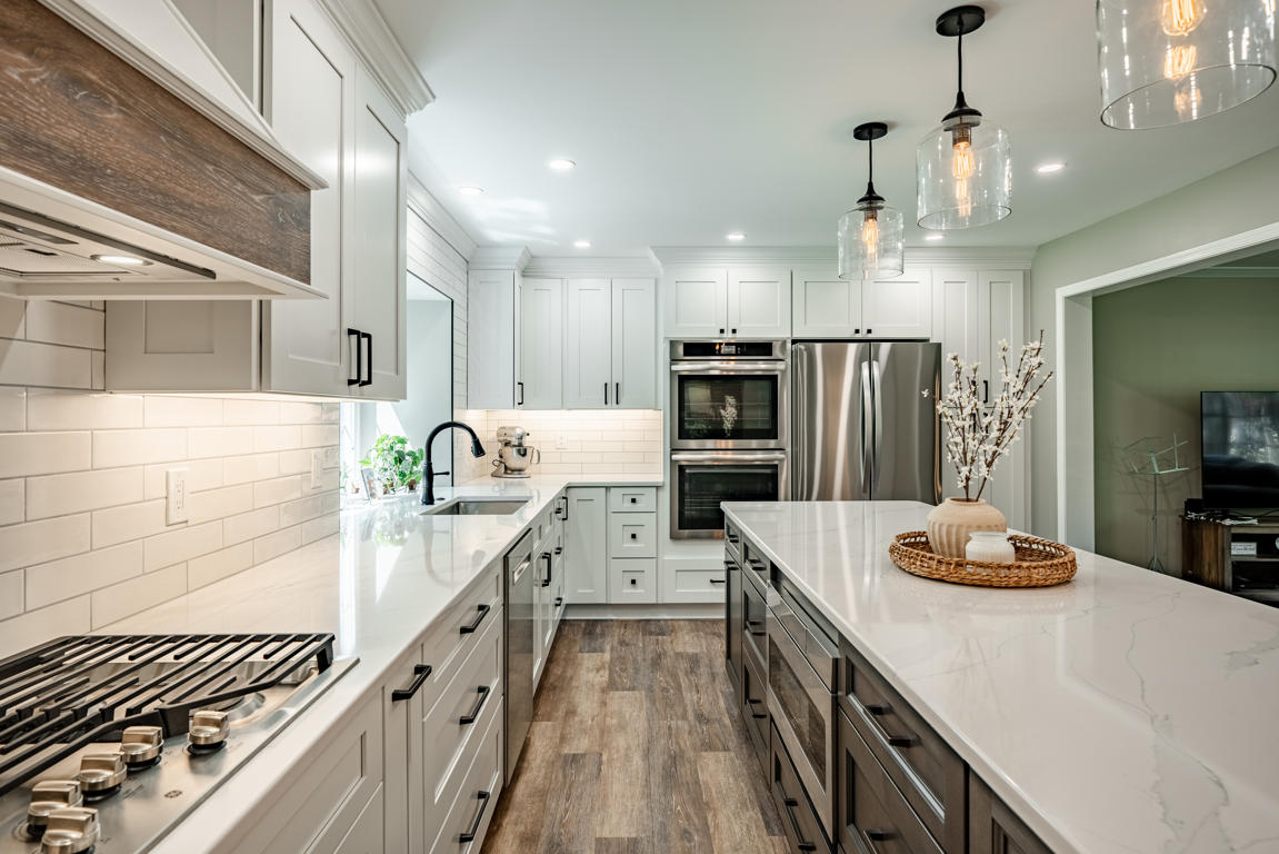 Gas cooktop with stainless steel appliances, custom white range hood, and dark stained kitchen island