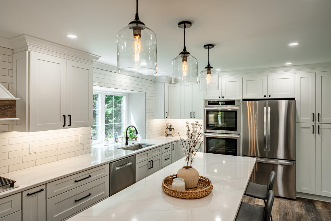 Full view of remodeled open concept kitchen showing pendant lighting, display niche, and cabinetry