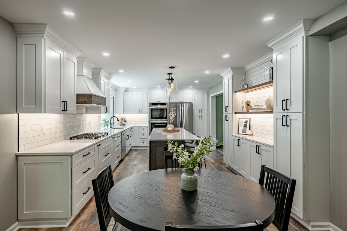 Exton kitchen overview with white shaker cabinets, dark island, and subway tile backsplash