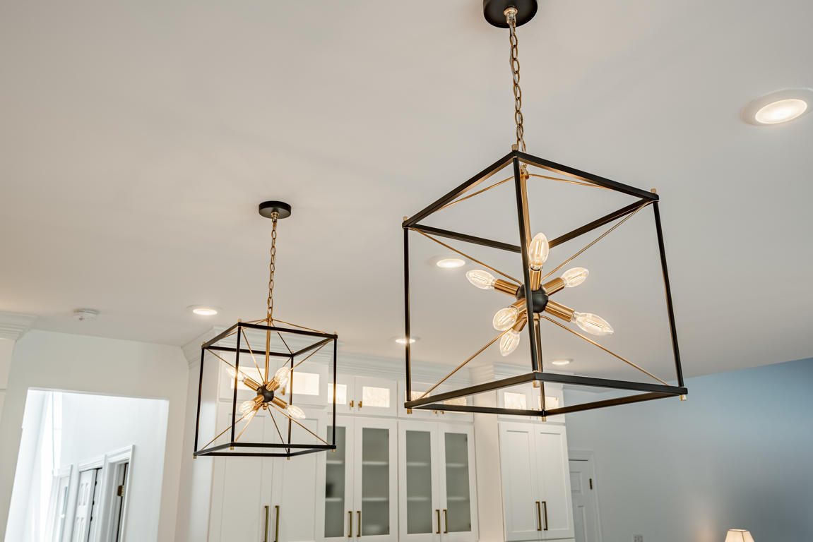 Galley corridor between island and perimeter showing hardwood floors, dual cabinet runs, and stainless appliances