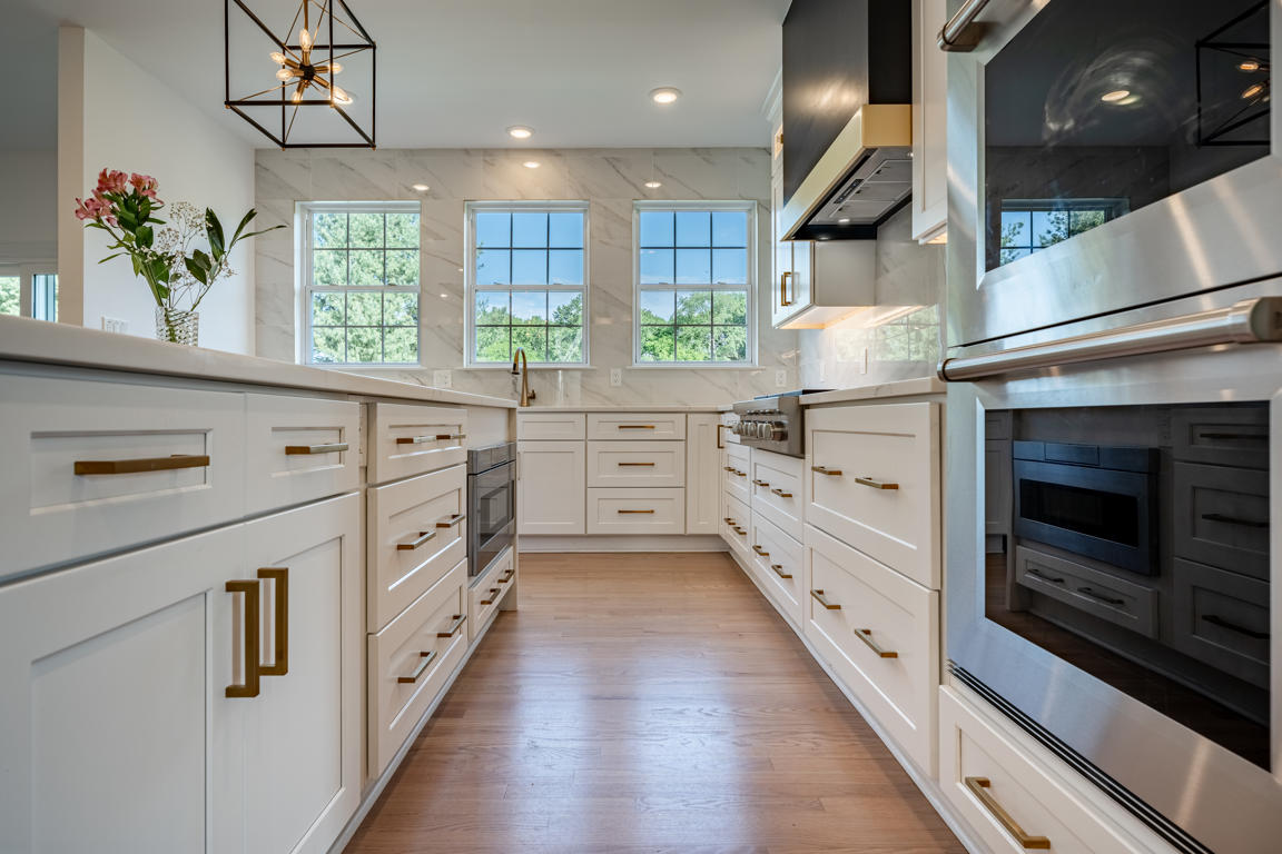 Kitchen cabinetry detail showing crown molding, white shaker style doors, and brushed gold knobs and pulls
