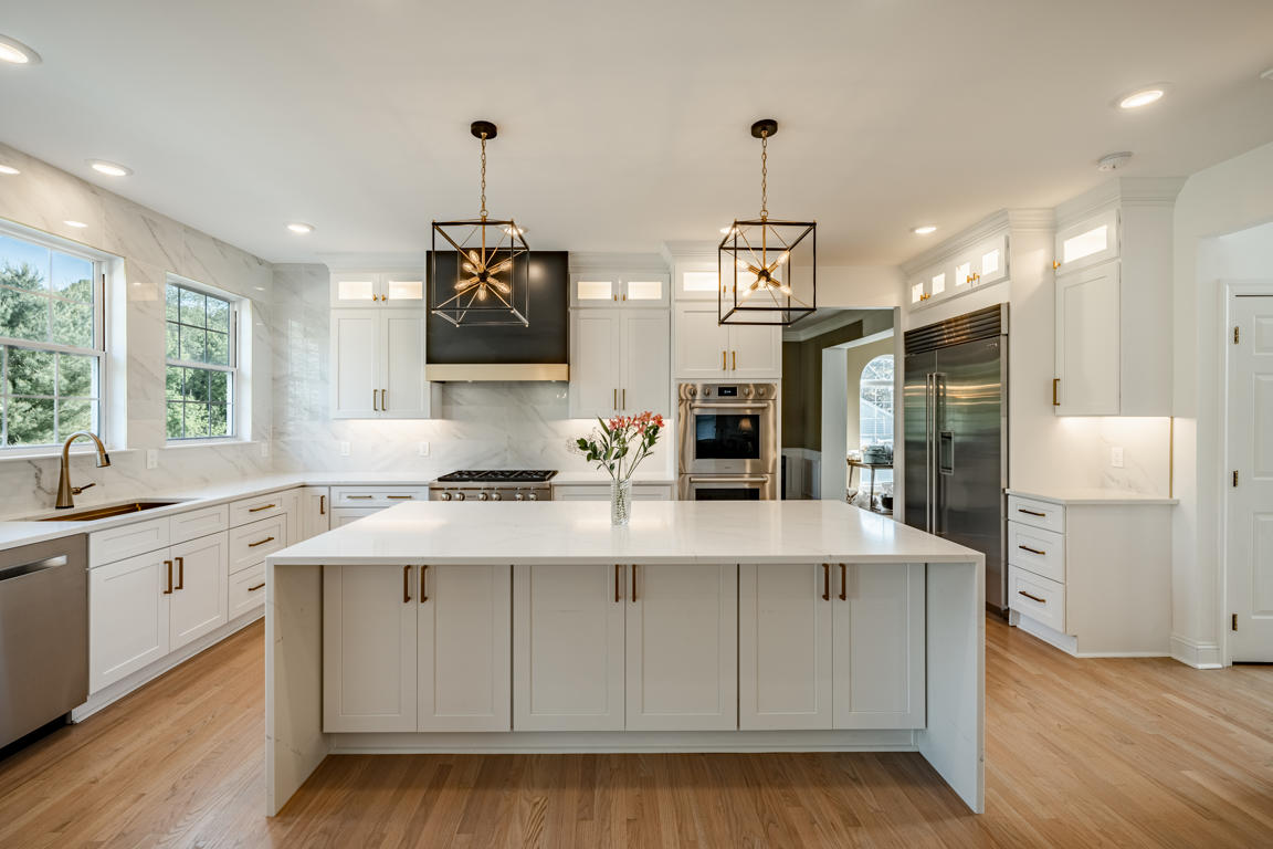 Full-height marble-look porcelain backsplash behind range with matte black hood and brushed gold band detail
