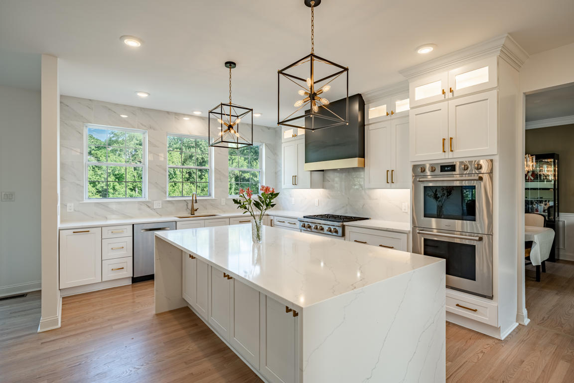 Glass-front upper cabinets with frosted glass doors, illuminated interior shelves, and lit transom windows above