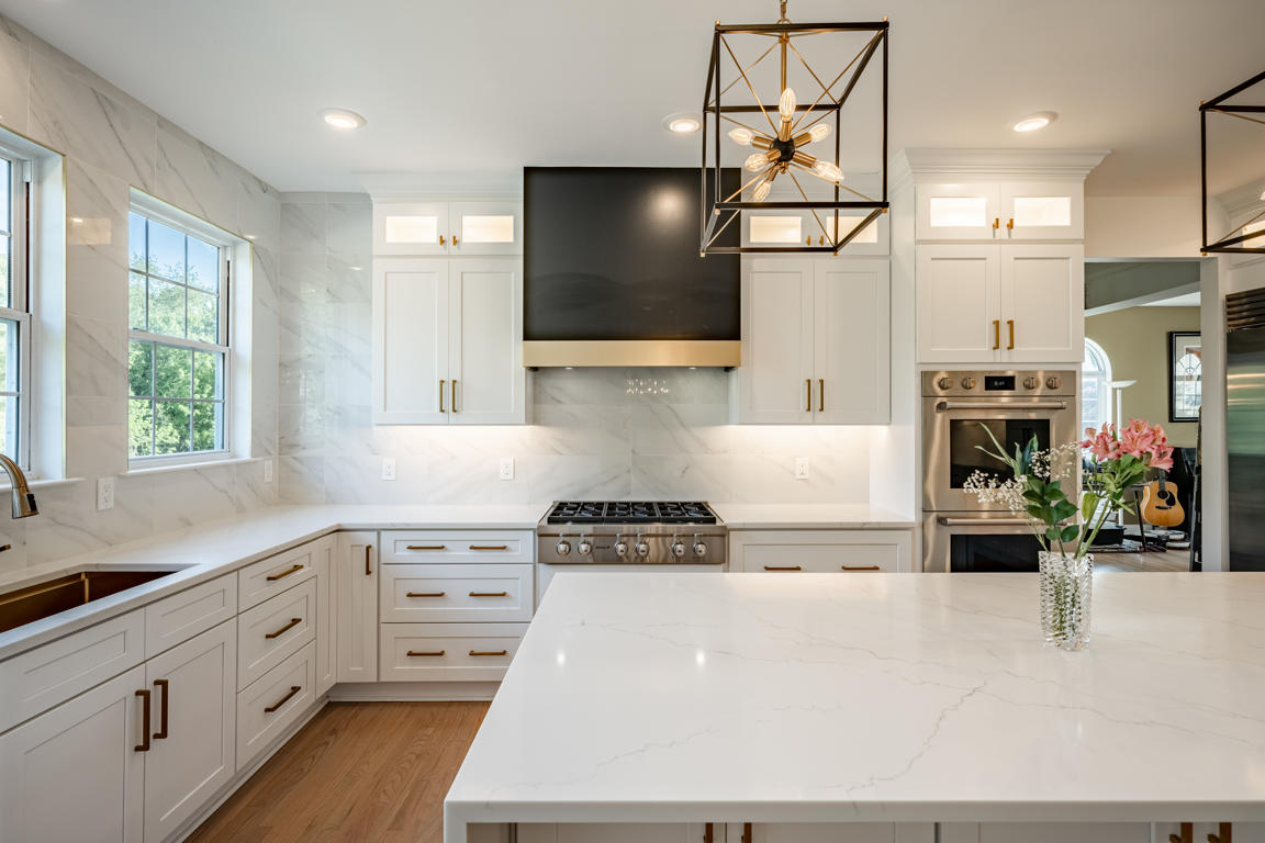 Gold undermount sink close-up with pull-down faucet, quartz countertop, and natural light from triple windows