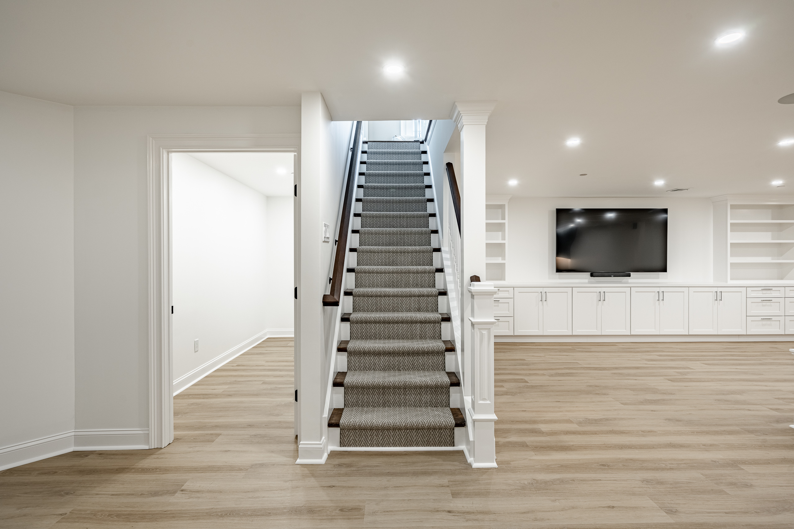 Basement remodel Newtown Square - staircase with herringbone carpet runner and entertainment center