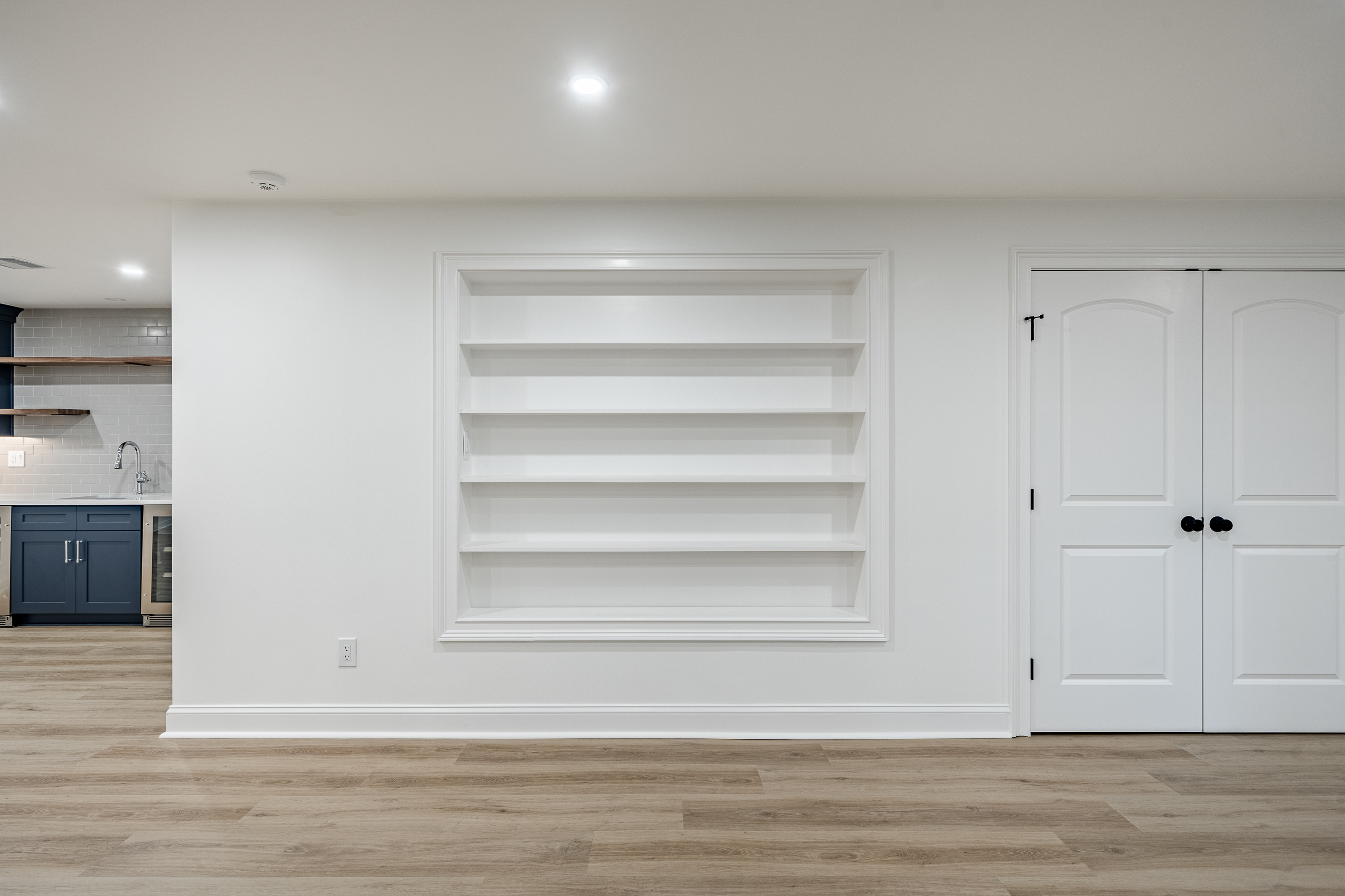 Newtown Square PA basement renovation - built-in recessed shelving and navy blue kitchenette