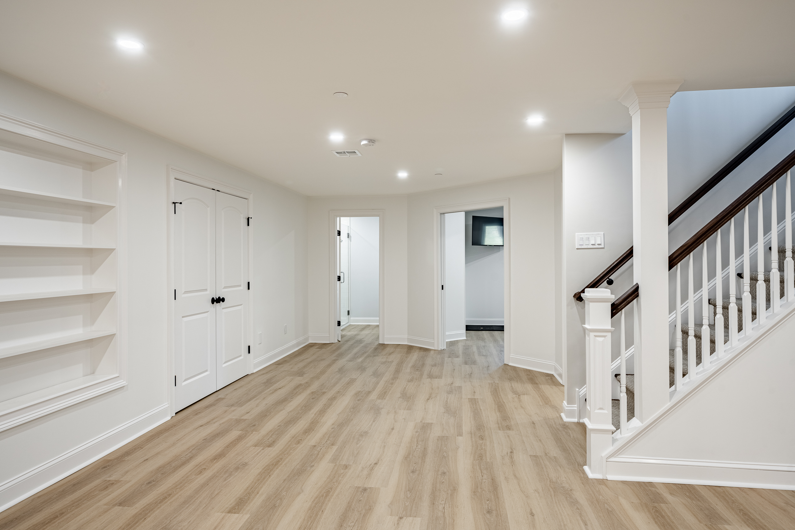 Basement renovation Delaware County - light wood floors with staircase and built-in shelving