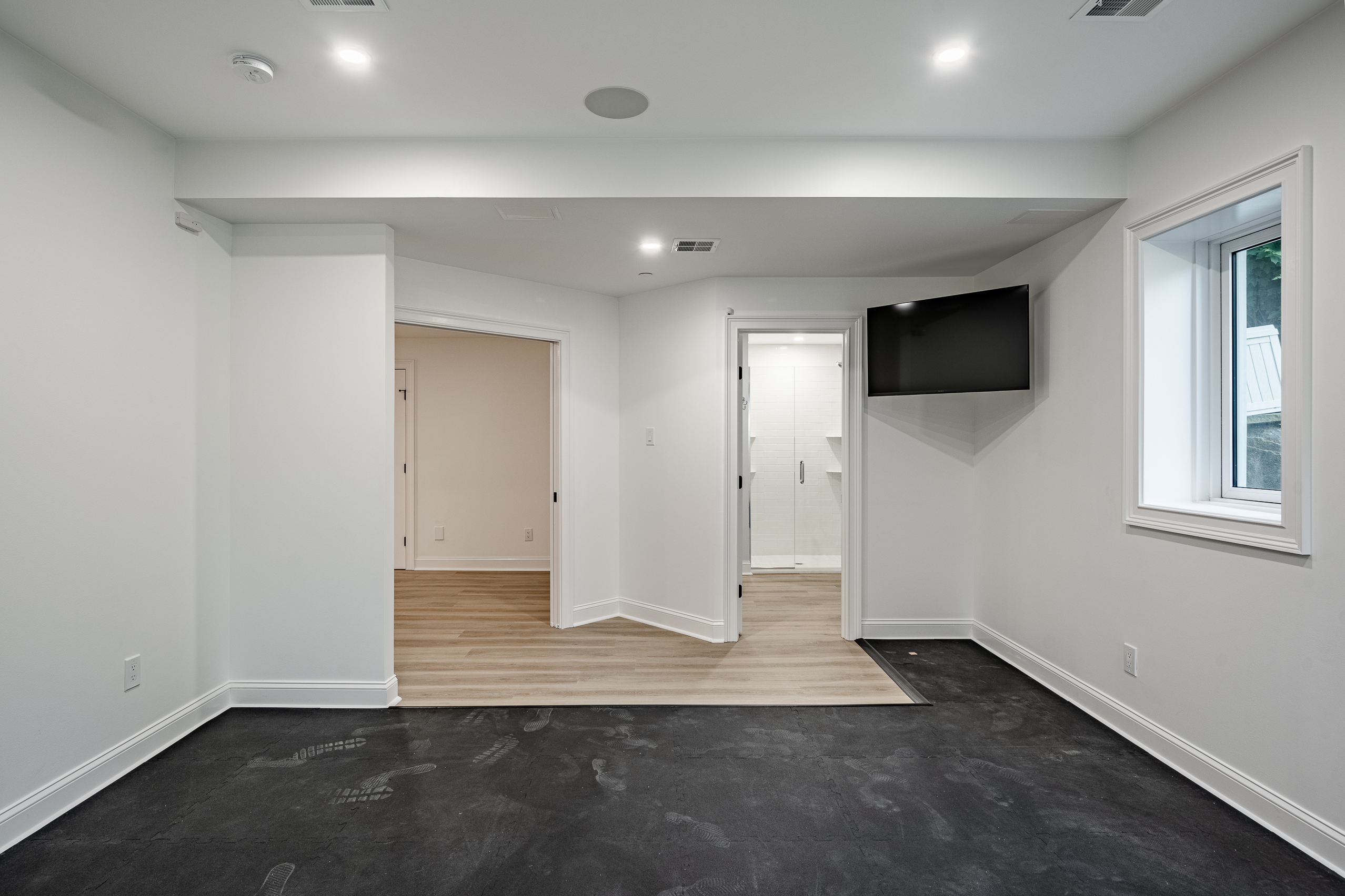 Basement gym renovation - rubber floor with mounted TV and bathroom access