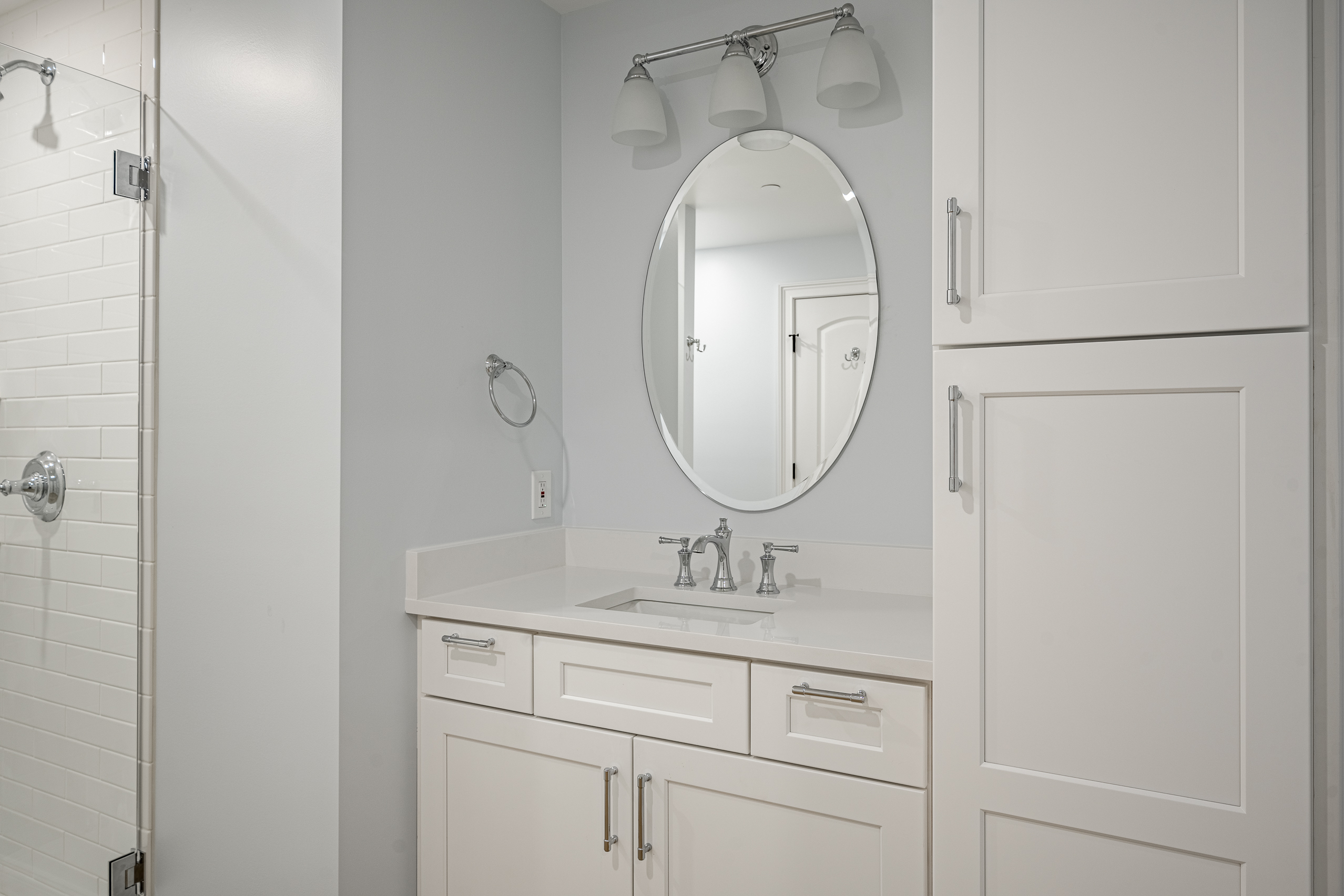 Basement bathroom Newtown Square - vanity with oval mirror and storage cabinet