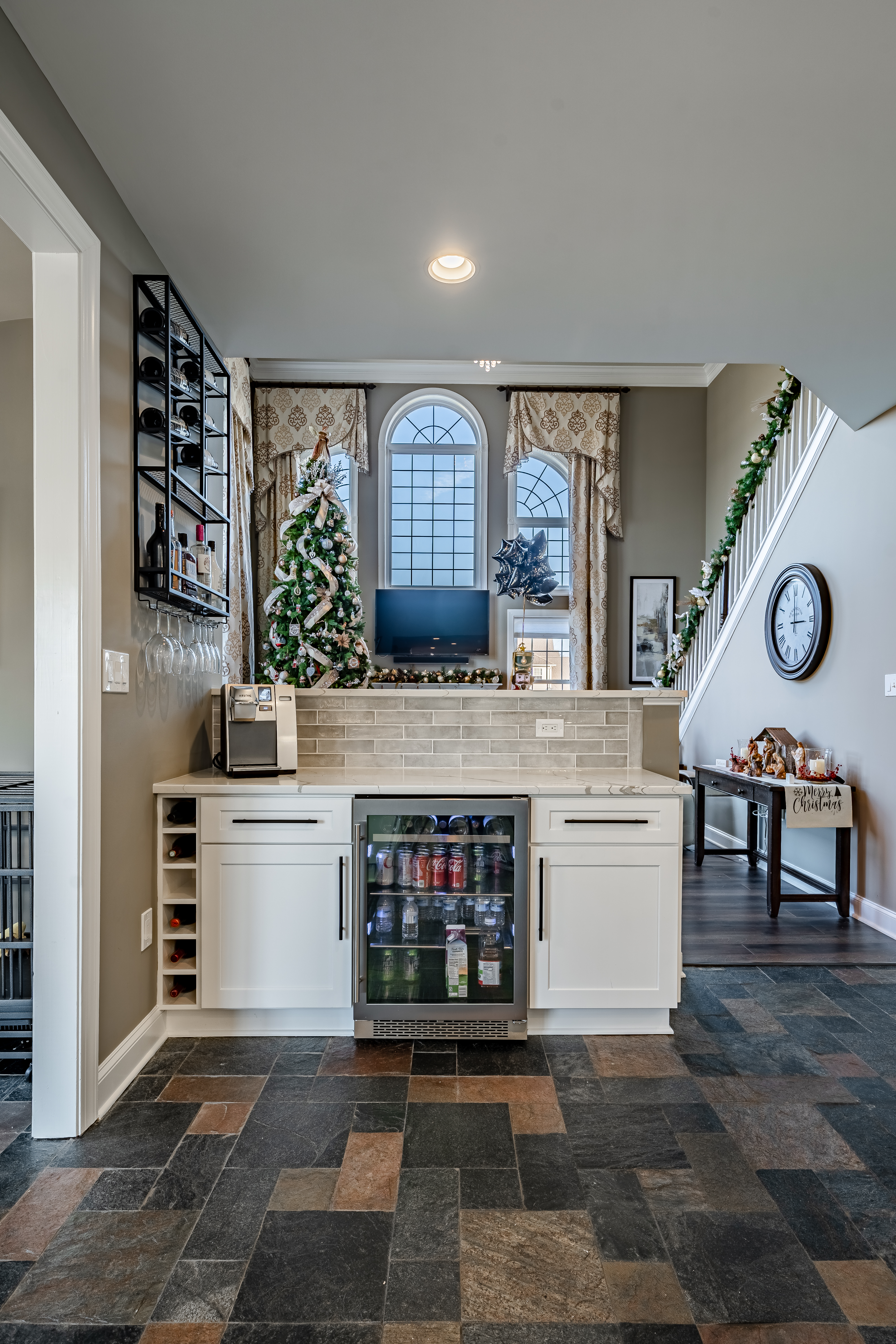 Built-in beverage station - white cabinets with glass-front beverage refrigerator, wine storage, wall-mounted wine rack, and subway tile backsplash