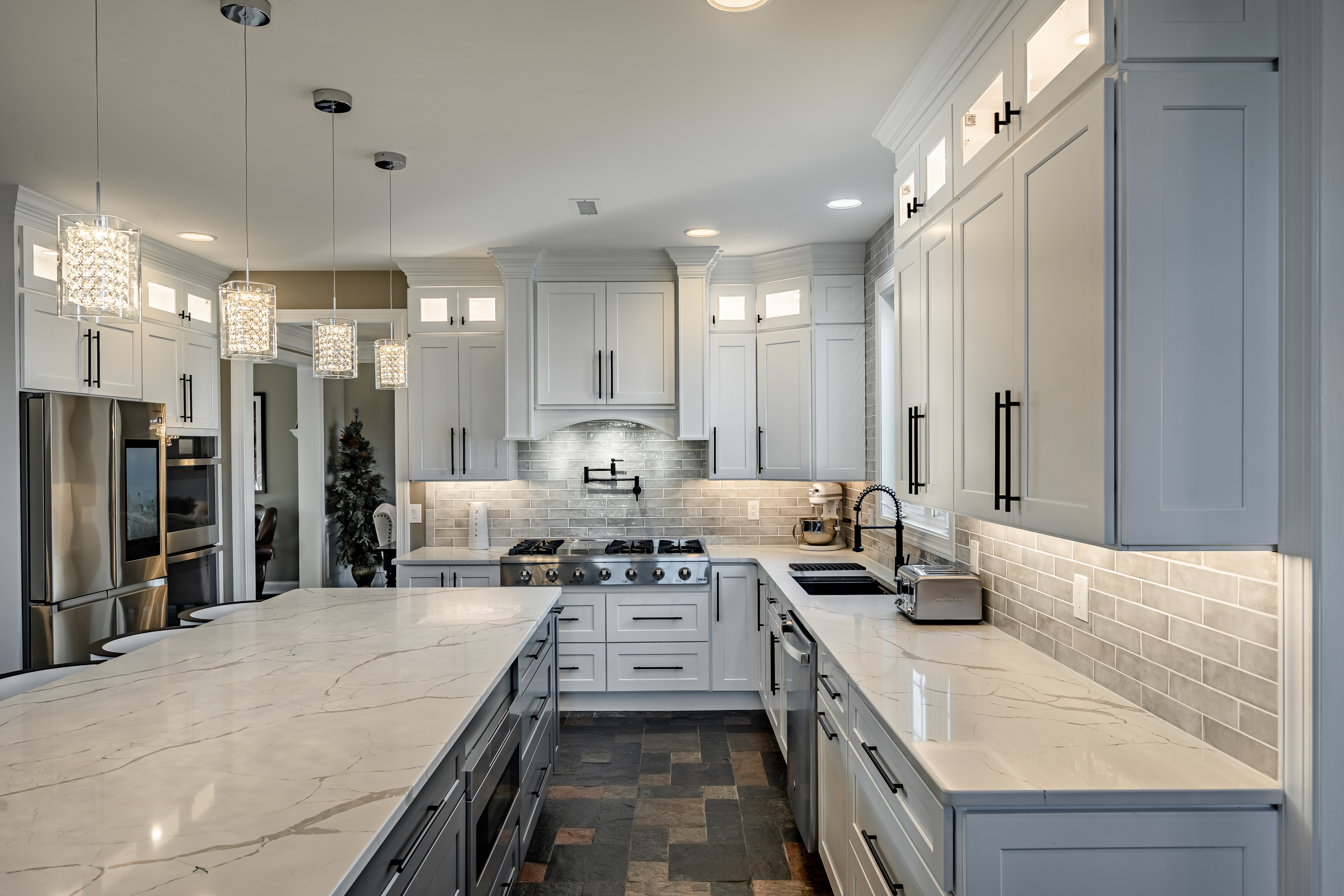 Kitchen remodel West Brandywine PA - view across quartz countertops showing custom range hood, crystal pendants, and subway tile backsplash