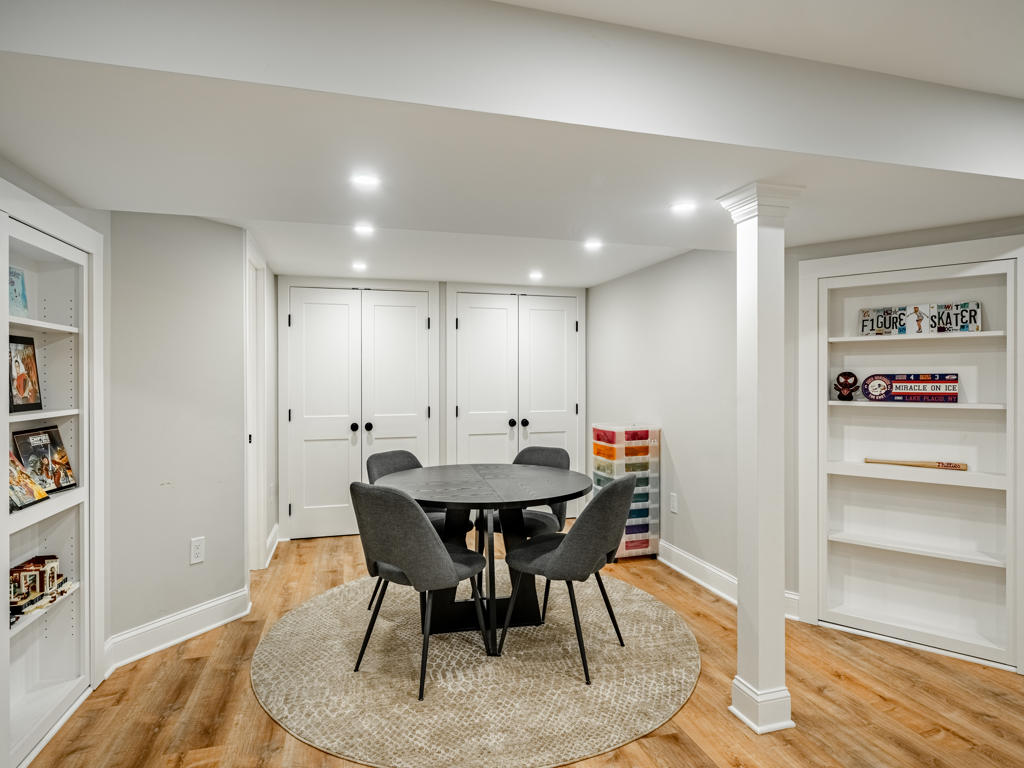 Game room in West Chester finished basement with custom built-in shelving, round dining table, and open view toward main entertainment area