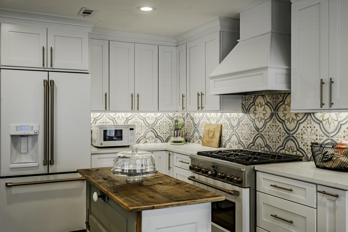 Sage green vintage rolling island with weathered wood top, caster wheels, and cookbook storage in farmhouse kitchen