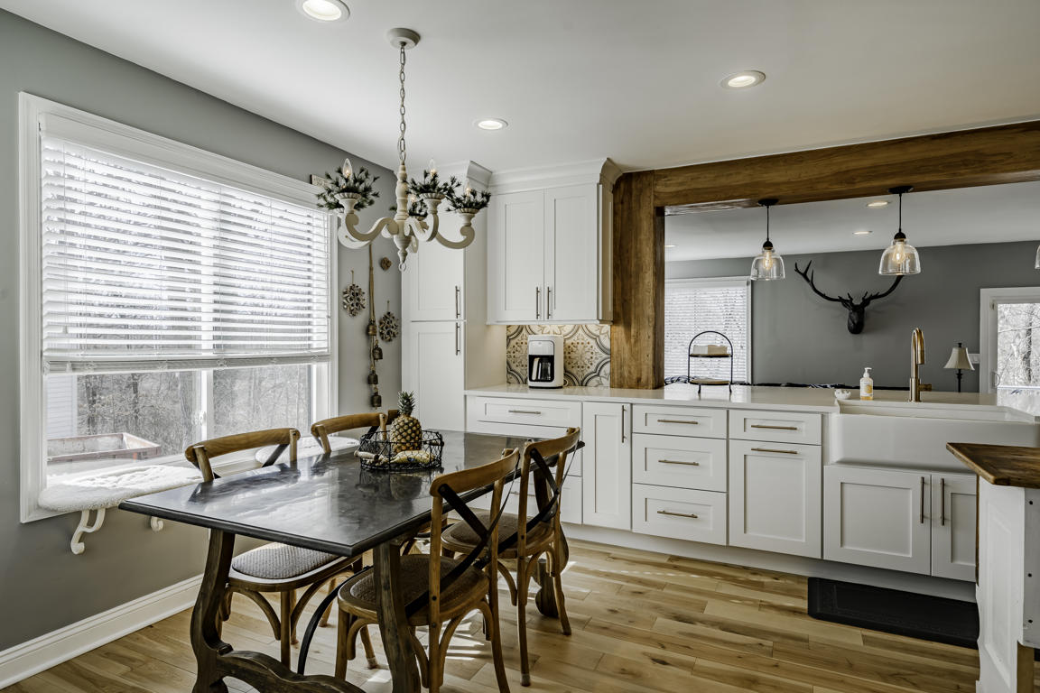 Pendant light and peninsula detail with bar stools, quartz countertop, and view into family room beyond
