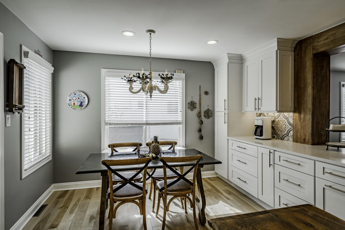 White shaker upper cabinets with crown molding, recessed lighting, and decorative backsplash tile meeting ceiling