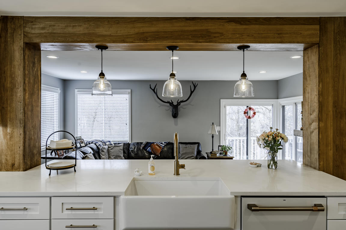 Kitchen window above sink with natural light illuminating quartz countertop and brass fixtures