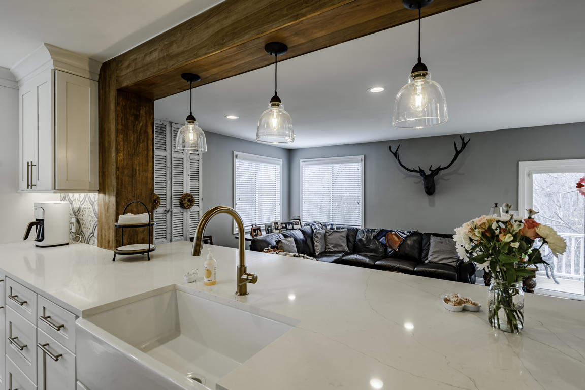 Kitchen ceiling with evenly spaced recessed LED lighting and clear glass pendant fixtures over peninsula