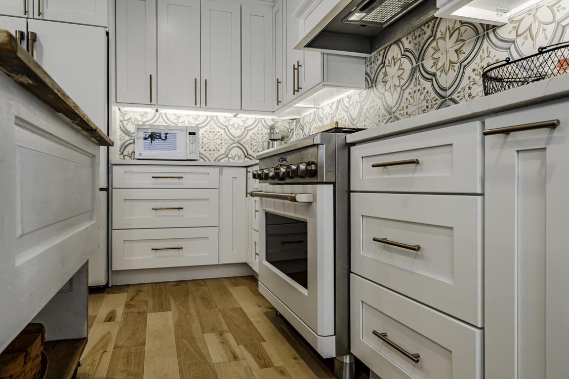 White paneled range hood with crown molding detail and decorative cement tile backsplash beneath