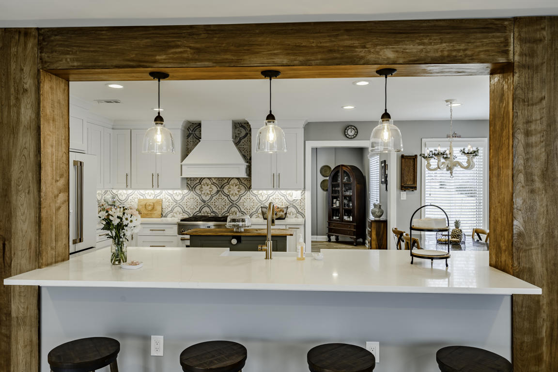 Sage green rolling island positioned between range wall and peninsula with cookbook shelving below