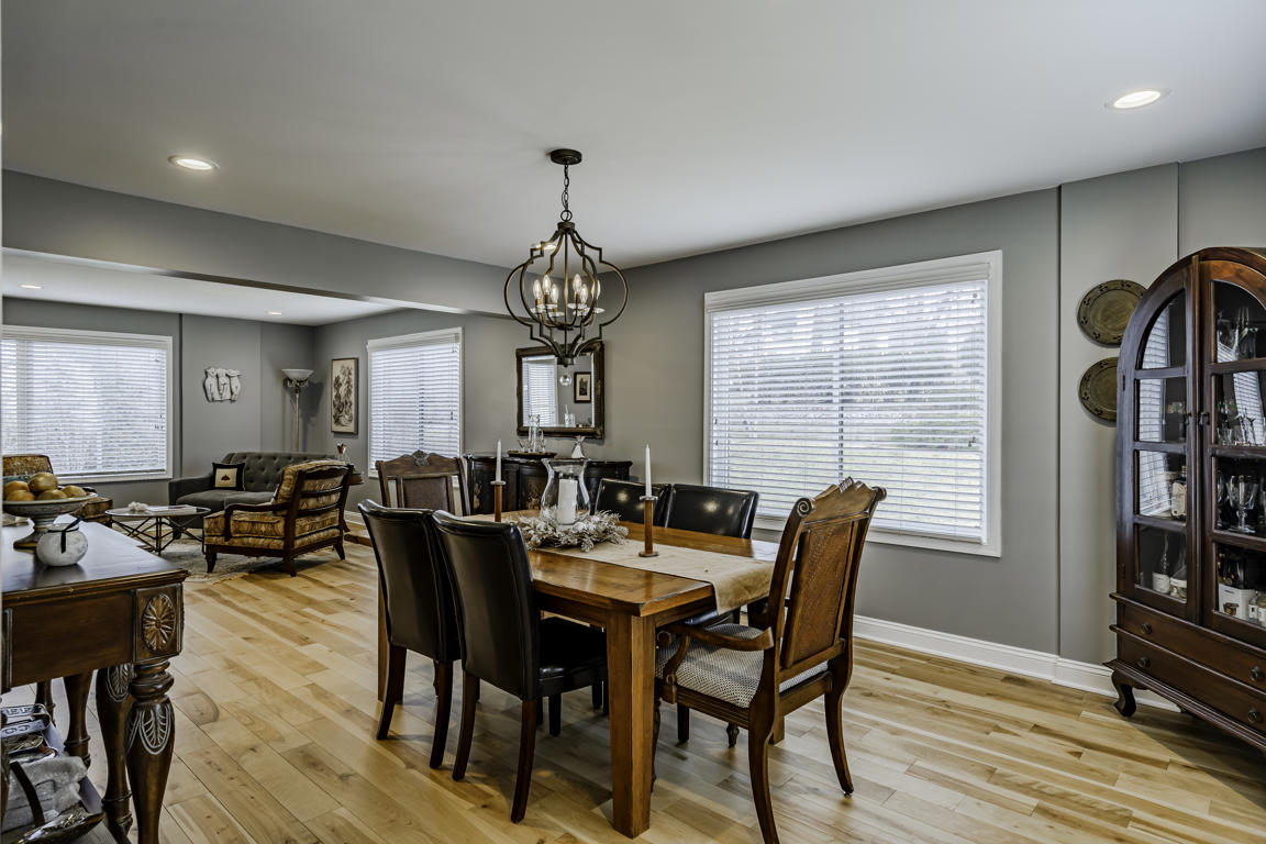 Formal dining room with farmhouse table, ornate chandelier, gray walls, and arched china cabinet