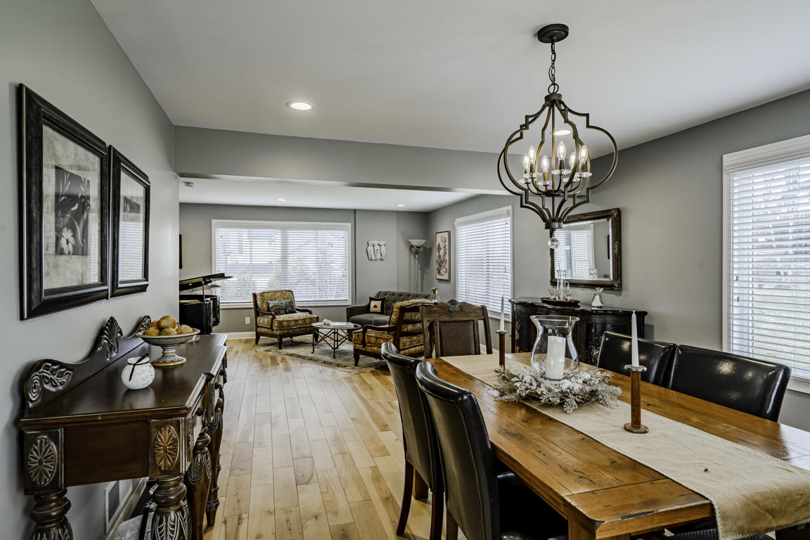 Dining room from opposite angle showing chandelier, carved buffet sideboard, framed artwork, and hickory floors