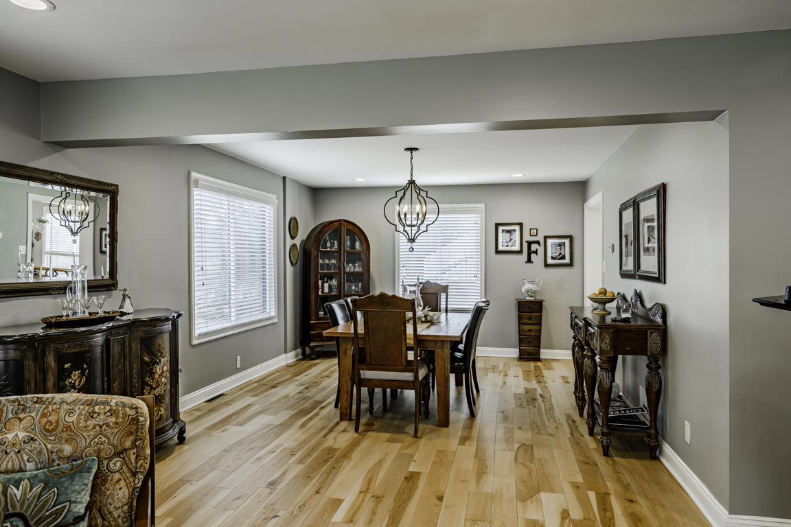 Dining room from living room perspective with farmhouse table, china cabinet, chandelier, and gallery wall