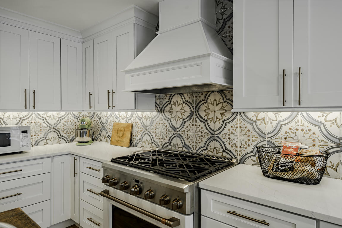 Kitchen peninsula with quartz countertop, clear glass bell pendant lights with brass accents, and dark wood bar stools