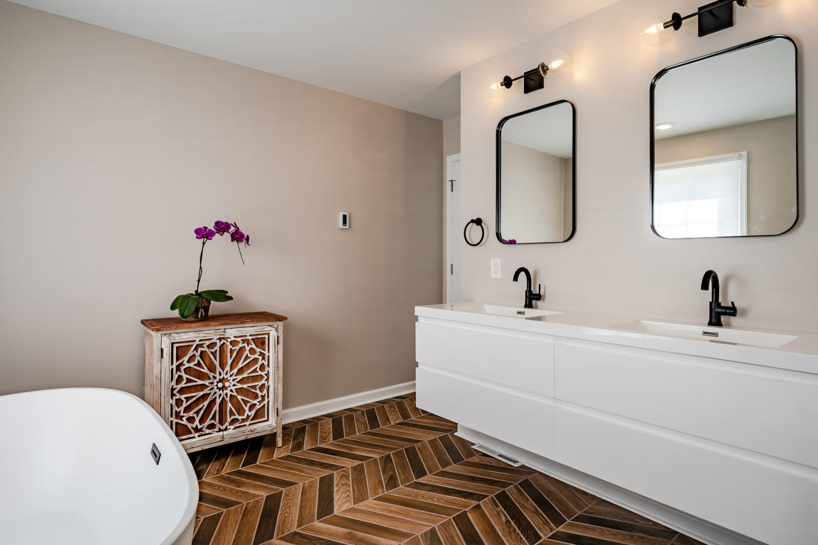 Two-light vanity fixture with clear glass globe shades in matte black finish mounted above bathroom mirror