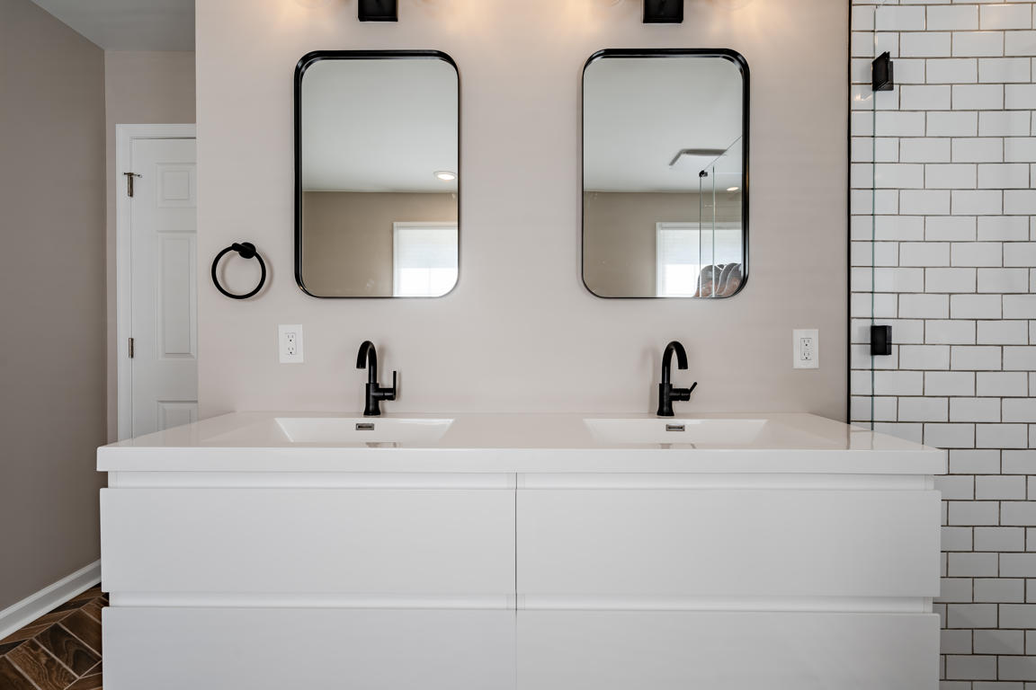White subway tile shower wall with gray grout lines and recessed penny round mosaic niche with black metal frame