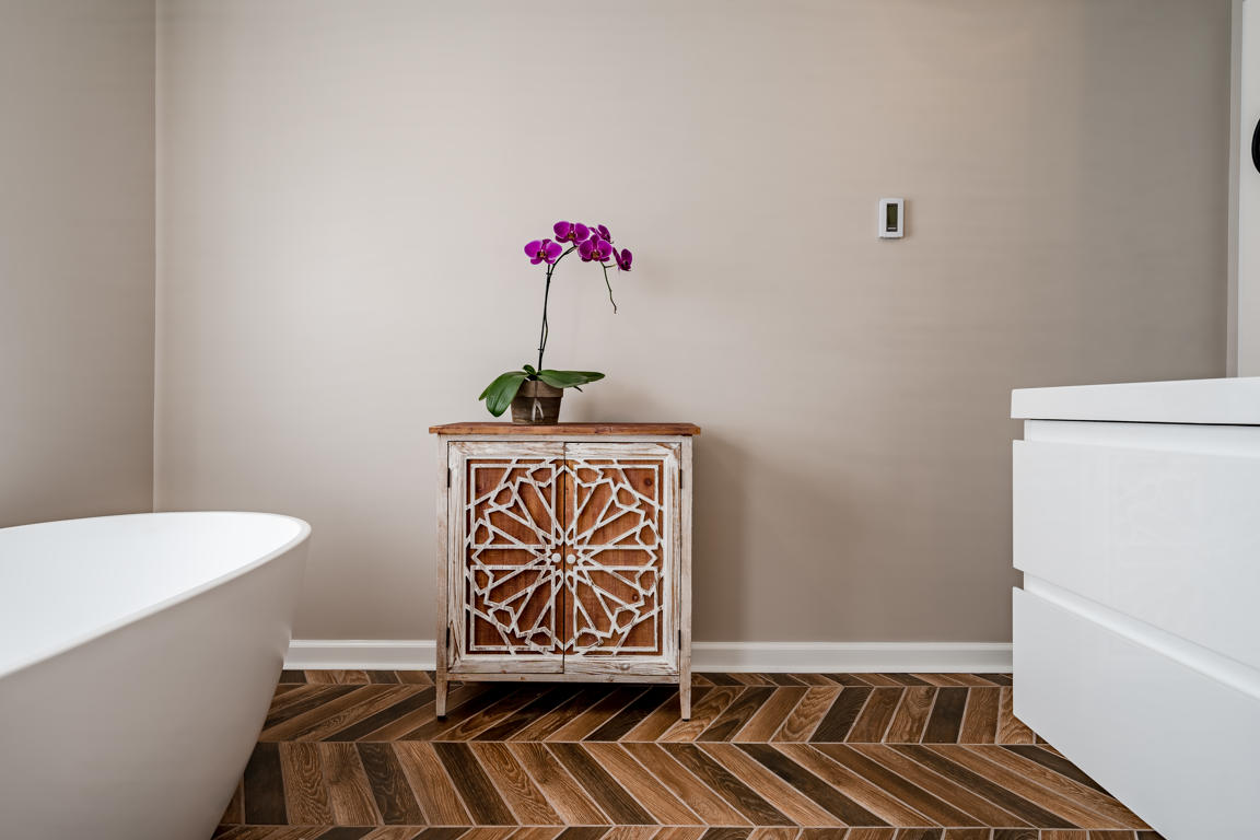 Accent cabinet and orchid detail with herringbone tile floor pattern and warm greige wall color