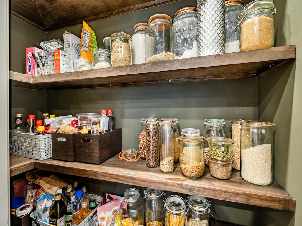 Interior of custom walk-in pantry in West Chester PA kitchen with deep olive walls and custom floating wood shelves with organized dry goods storage
